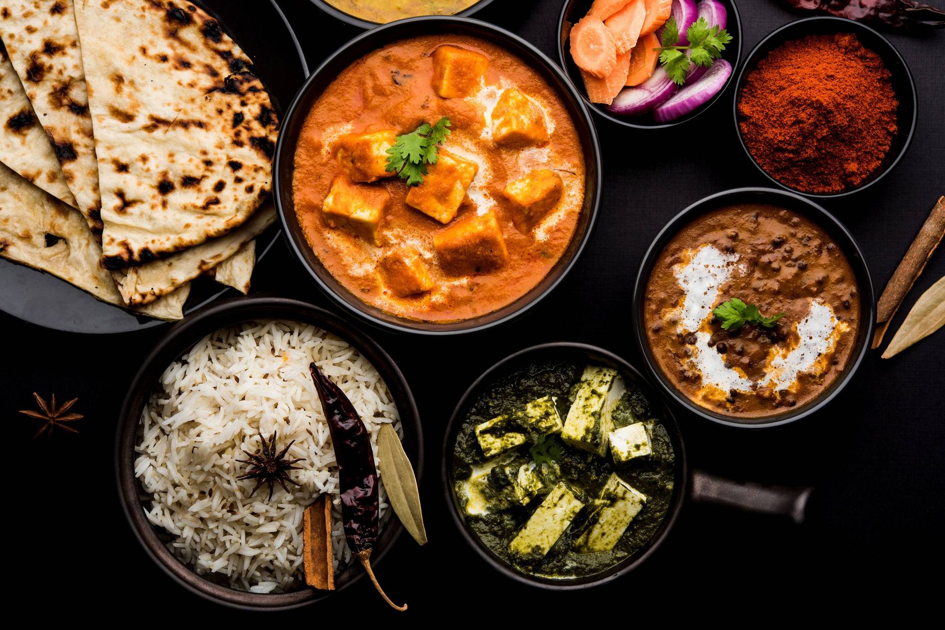 Paneer butter masala, dal makhani, palak paneer, basmati rice and fresh naan on the table at Nawab